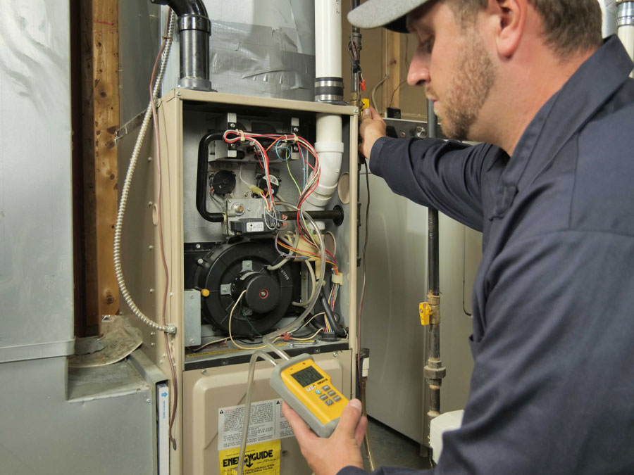 A Lancaster Heating and Cooling service technician inspects a residential furnace.